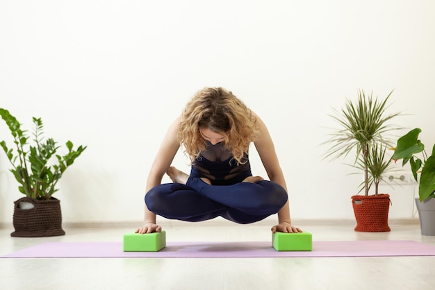 Młoda kaukaska kobieta jogin trenuje z cegłami w studio jogi Styl życia