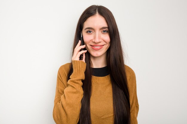 Młoda kaukaska kobieta korzystająca z telefonu komórkowego na białym tle