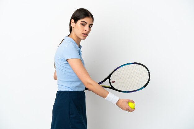 Młoda kaukaska kobieta na białym tle gra w tenisa