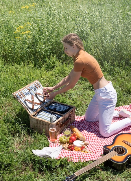 Młoda kaukaska kobieta przygotowuje kosz piknikowy na zewnątrz, gotowa na piknik