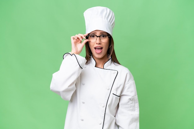 Młoda kaukaska kobieta szefa kuchni na odosobnionym tle w okularach i zaskoczona