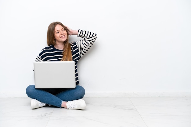 Młoda kaukaska kobieta z laptopem siedząca na podłodze na białym tle uświadomiła sobie coś i zamierza znaleźć rozwiązanie