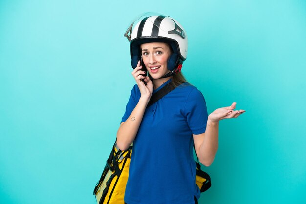 Młoda kaukaska kobieta z termicznym plecakiem na białym tle prowadząca rozmowę z telefonem komórkowym z kimś