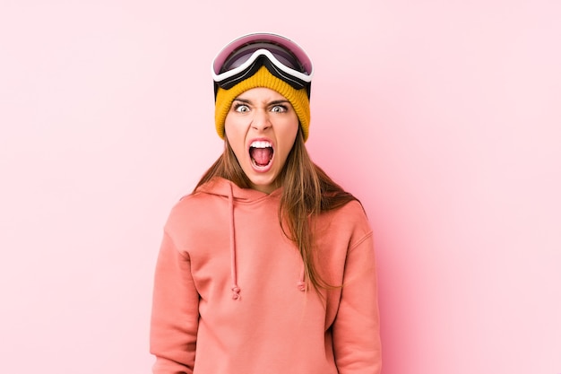 Młoda kaukaski kobieta ubrana w stroje narciarskie na białym tle krzycząc bardzo zły i agresywny.
