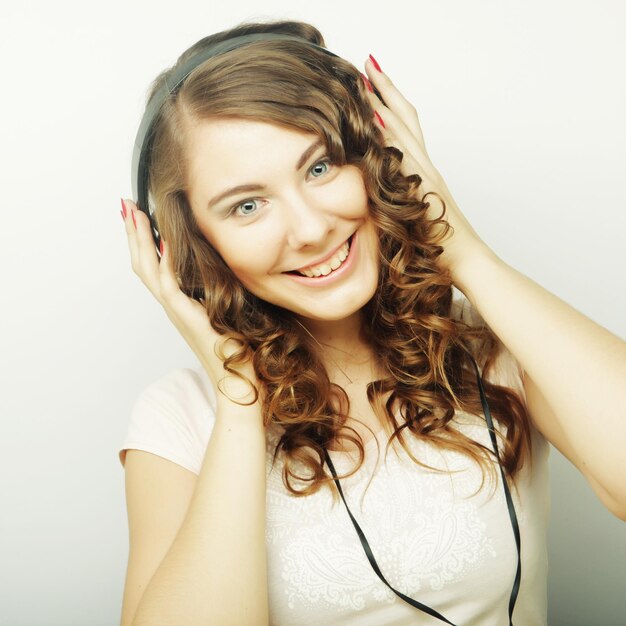 Młoda kędzierzawa kobieta ze słuchawkami słucha muzykiStudio shot