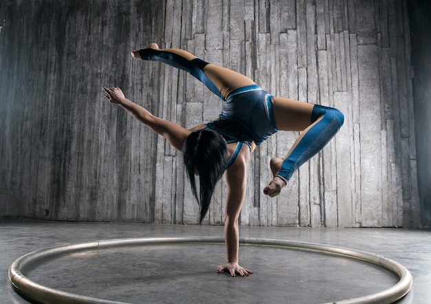 Młoda Kobieta Acrobat Stojąc Na Dłoni Na Szarej Powierzchni W Studio Fotograficznym