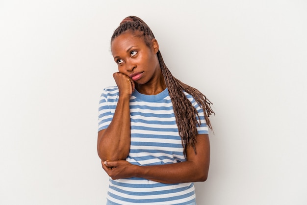 Młoda kobieta african american na białym tle, która czuje się smutna i zamyślona, patrząc na miejsce.