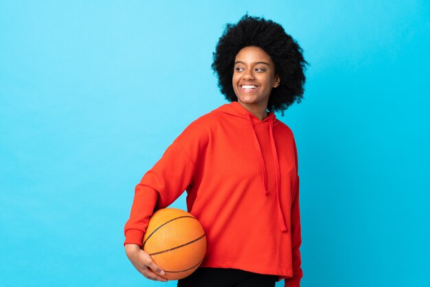Młoda kobieta Afroamerykanów samodzielnie na niebiesko gry w koszykówkę