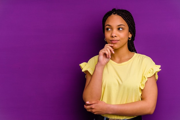 Młoda kobieta Afroamerykanów samodzielnie na żółtym tle Młoda kobieta Afroamerykanów samodzielnie na żółtym tle patrząc w bok z wyrazem wątpliwości i sceptycyzmu.