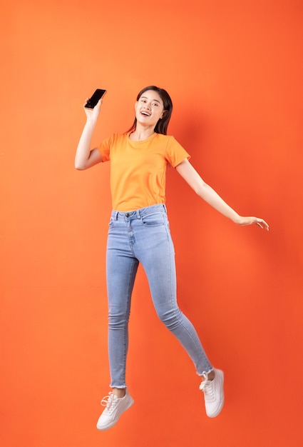 Młoda kobieta Azji ma na sobie pomarańczową koszulkę, skoki na pomarańczowo
