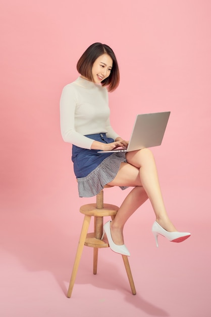 Młoda kobieta Azji za pomocą laptopa siedząc na krześle.