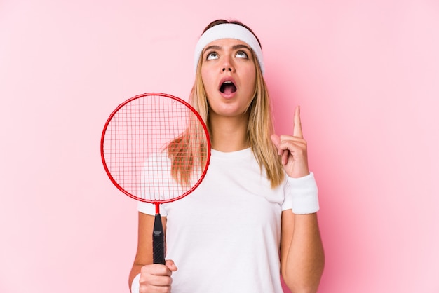 Młoda kobieta bawić się badminton odizolowywał wskazywać do góry z rozpieczętowanym usta.