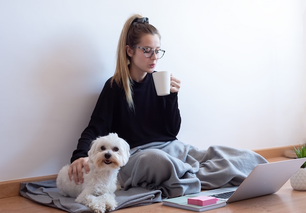 Zdjęcie młoda kobieta bawić się z jej psem i pije kawę w domu