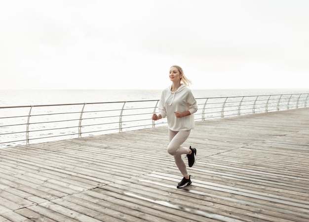 Młoda Kobieta Biegacz W Odzieży Sportowej ćwiczy Jogging Na Plaży. Trening Cardio