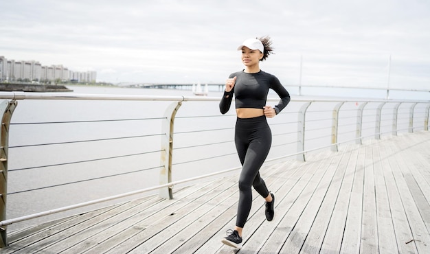 Młoda kobieta biegnąca sportowiec wykonująca ćwiczenia fitness na ćwiczenia cardio używa inteligentnego urządzenia śledzącego zegarek na dłoni