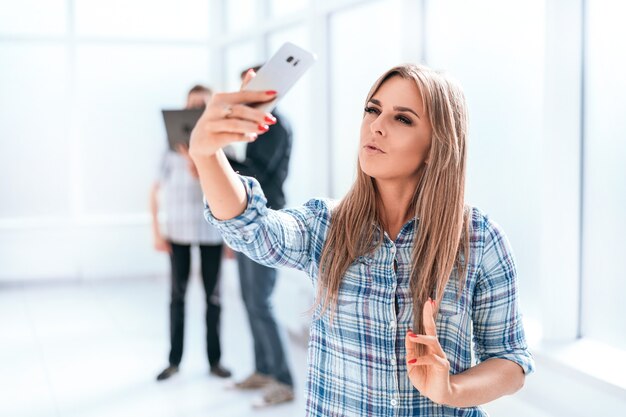 Młoda kobieta bierze selfie stojącego w biurze