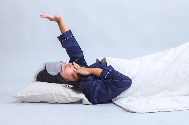 Młoda kobieta budząca się rano ziewa i rozciągająca się odizolowana na szarym tle