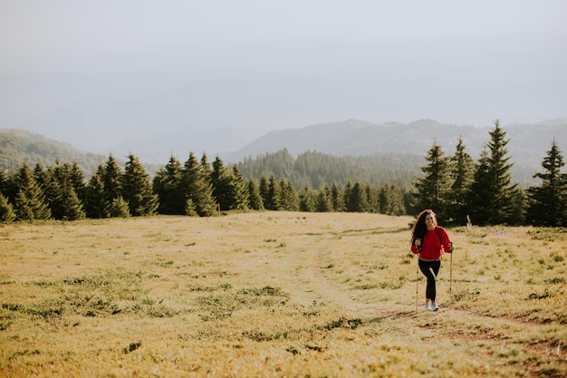 Młoda kobieta chodzi z plecakiem nad zielonymi wzgórzami