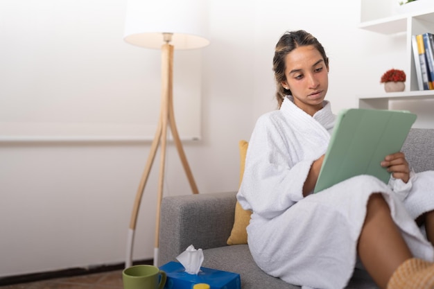 Młoda Kobieta Chora Siedzi Na Kanapie Podczas Pracy Z Cyfrowego Tabletu
