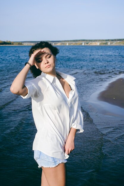 Zdjęcie młoda kobieta chroni oczy, stojąc przed morzem na plaży