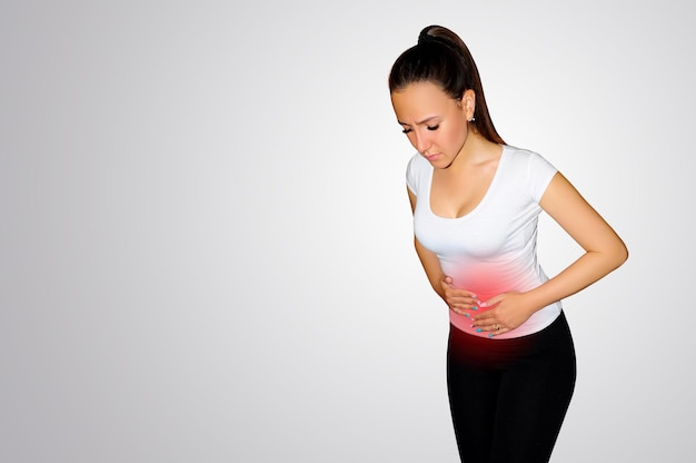 Młoda kobieta cierpi na ból brzucha. Miejsce bólu zaznaczone czerwoną plamką Pojęcie zdrowia