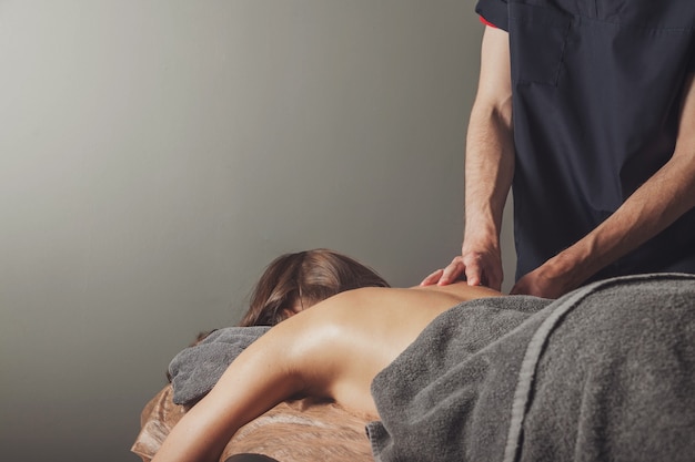 Młoda kobieta cieszy się sportowy masaż wellness w gabinecie lekarskim sali fitness. Profesjonalny masażysta domowy wykonuje ćwiczenia masażu. Pojęcie relaksu, urody, zdrowia, pielęgnacji ciała. Skopiuj miejsce