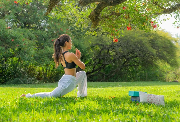 Młoda kobieta ćwiczy jogę pod drzewem w koncepcji ParkWellness