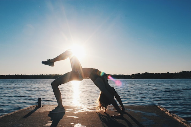 Zdjęcie młoda kobieta ćwiczy na plaży przy jasnym niebie