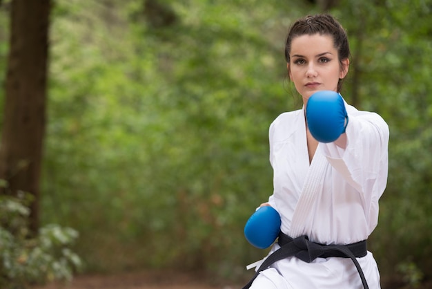 Młoda Kobieta ćwiczy Swoje Ruchy Karate W Zalesionym Obszarze Leśnym Biały Czarny Pas W Kimono