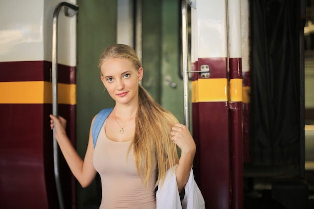 Młoda kobieta czeka w zabytkowym pociągu, zrelaksowana i beztroska na peronie