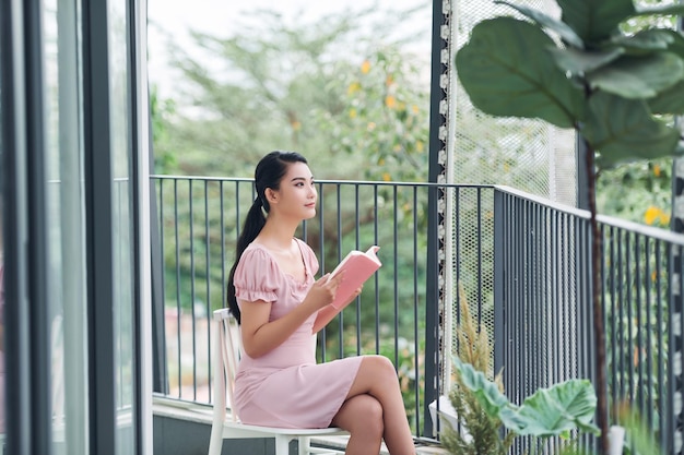 Młoda kobieta czyta książkę na balkonie