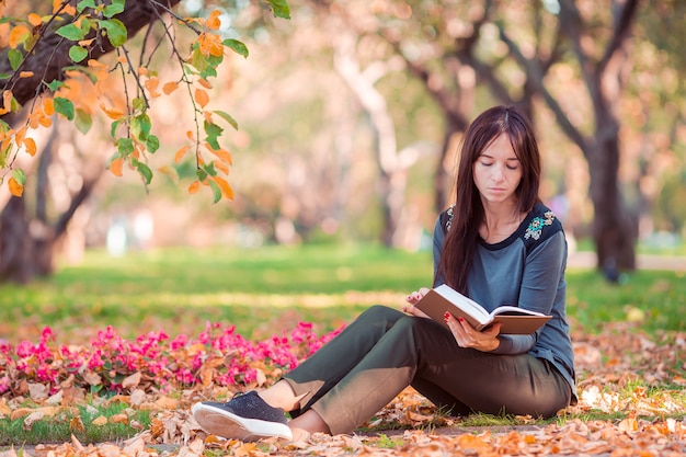 Młoda kobieta czyta książkę w pięknym jesień parku