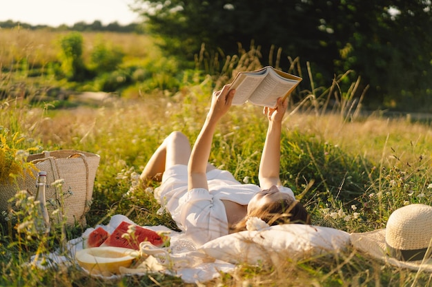 Zdjęcie młoda kobieta czytająca książkę w polu na świeżym powietrzu czytanie i relaks czas letni