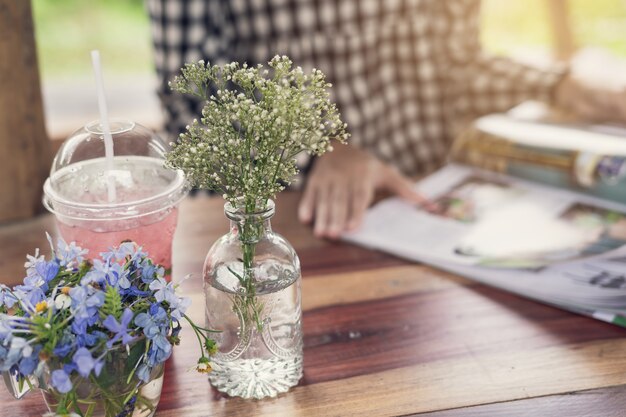 Młoda kobieta czytelniczy magazyn przy restauracją z sokiem i bukietem