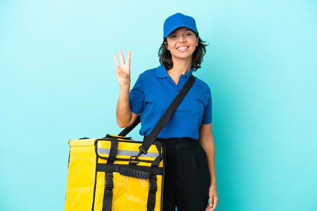 Młoda kobieta dostarczająca z plecakiem termicznym szczęśliwa i licząca trzy palcami