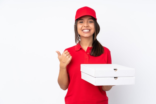 Młoda kobieta dostawy pizzy na białym tle, wskazując na bok, aby przedstawić produkt