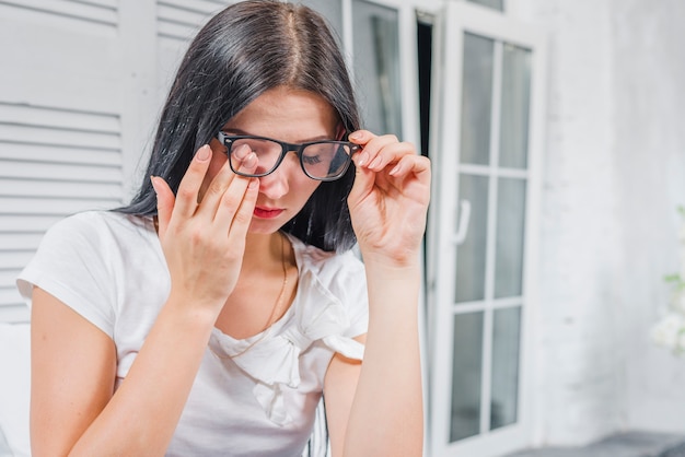 Młoda Kobieta Dotyka Jej Oczy Pod Eyeglasses