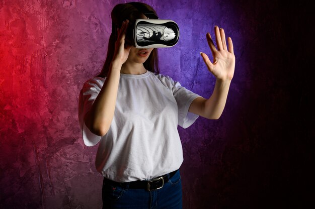 Młoda kobieta dotyka powietrza podczas doświadczenia VR. Niebieska i czerwona ściana