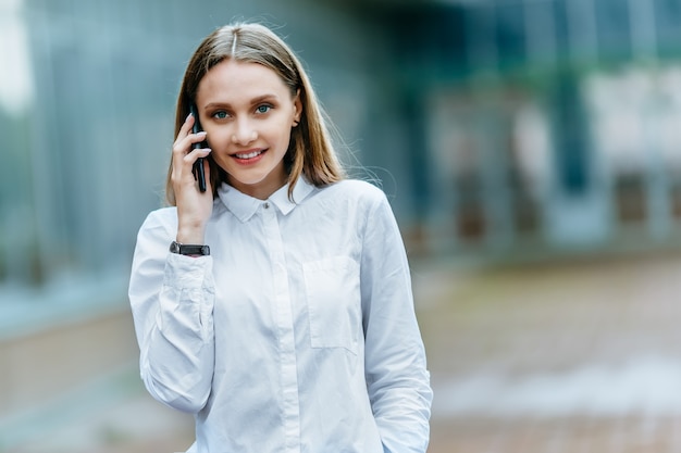 Młoda kobieta dzwoni na telefonie. Atrakcyjny bizneswoman opowiada telefonem. . Technologia internet i koncepcja szczęśliwych ludzi.