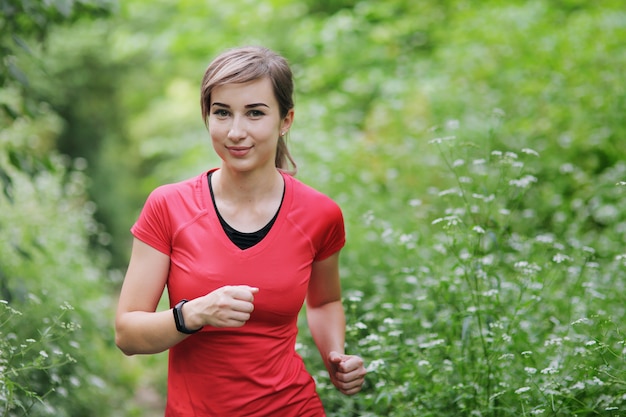 Młoda kobieta fitness działa na szlaku lasu rano.