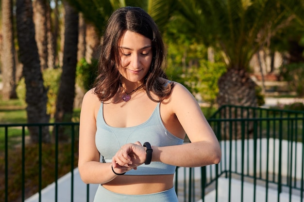 Młoda kobieta fitness patrzy na swój elektroniczny zegarek na zewnątrz
