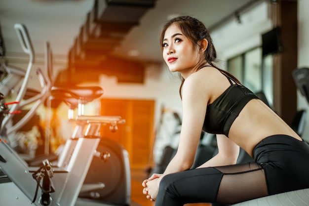 Młoda kobieta fitness zmęczona siłownią pije koktajl proteinowy, ćwicząc koncepcję sprawności i zdrowego stylu życia