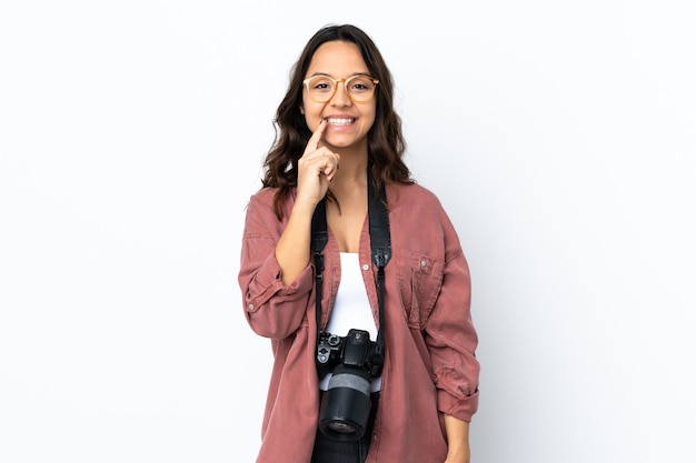 Młoda kobieta fotograf na pojedyncze białe tło wykazujące znak gestu ciszy wkładając palec do ust