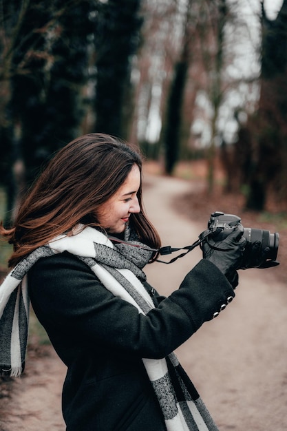 Zdjęcie młoda kobieta fotografuje kamerą w lesie