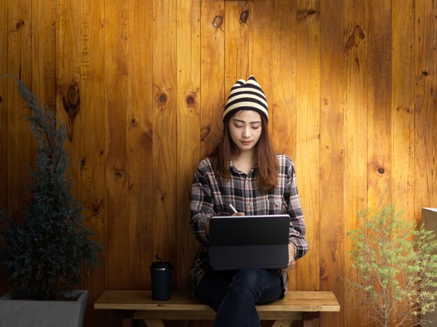 Młoda kobieta freelancer budzi się nad swoim projektem z tabletem, siedząc w wygodnym miejscu do pracy