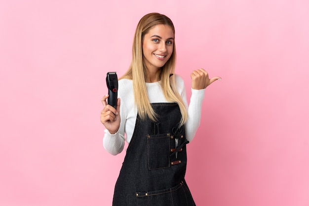 Młoda kobieta fryzjer na różowo, wskazując na bok, aby przedstawić produkt
