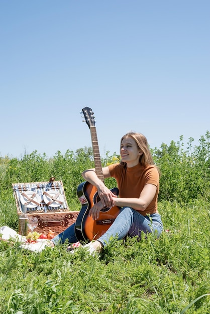 Młoda kobieta gra na gitarze na pikniku