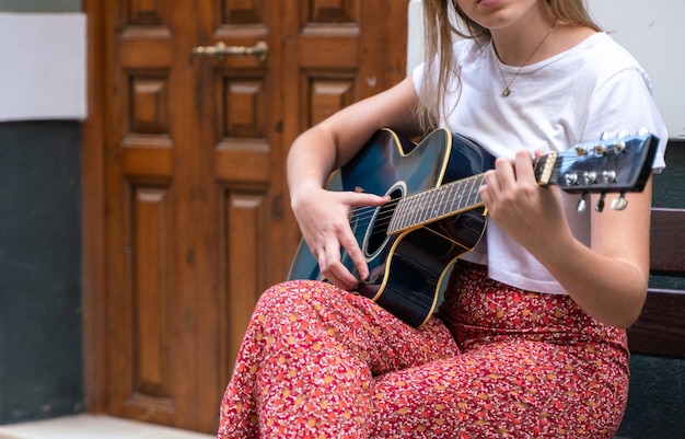Młoda kobieta gra na gitarze na ulicy