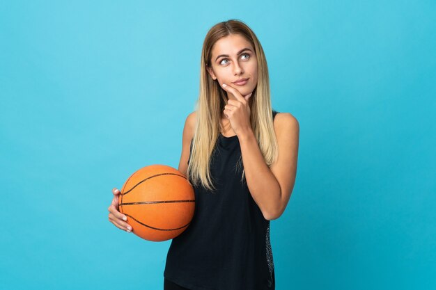 Młoda kobieta gra w koszykówkę na białym tle i patrząc w górę