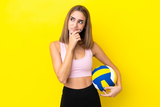 Młoda kobieta gra w siatkówkę na białym tle na żółtym tle ma wątpliwości